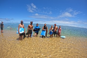 a group of people standing on top of a sandy beach